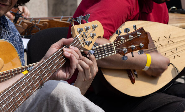Close up of musicians playing acoustic string instruments and lute during an outdoor live performance