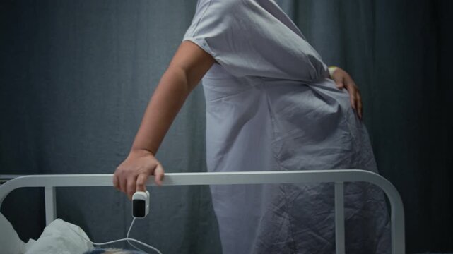 Pregnant Black woman holding hospital bed rail,breathing through labor contractions in maternity ward. Clip is ideal for maternal healthcare and childbirth education, close up