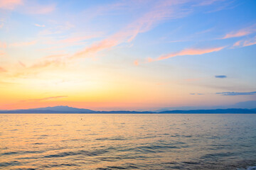 Obraz premium The sky is a beautiful shade of pink and orange, and the water is calm and still