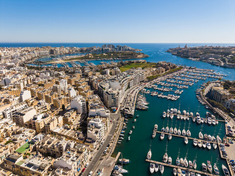 Aerial view of the Msida Marina filled with luxury yachts and boats surrounded by dense urban architecture and limestone buildings in Ta' Xbiex, Eastern Region, Malta.