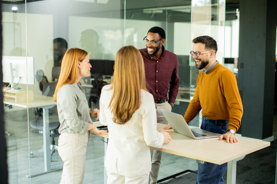 Group of coworkers discussing project in modern office space during afternoon meeting