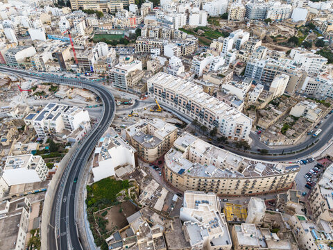 Aerial view of the Kappara flyover and dense residential apartment buildings with construction cranes in Msida, Eastern Region, Malta.