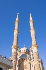 Obraz premium Al Sahaba Mosque in Sharm El Sheikh Egypt with twin minarets towering above the grand central dome showcasing magnificent Islamic architecture beneath a vivid blue sky in the summer time
