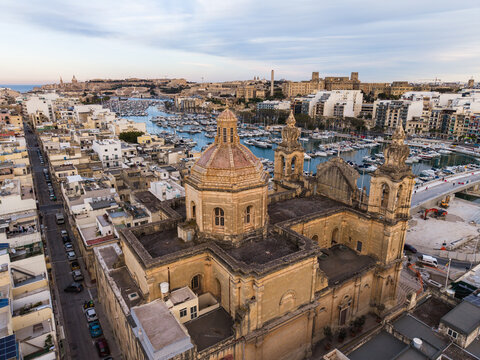 Aerial view of the Saint Joseph Parish Church with its prominent dome and bell towers overlooking the marina and urban rooftops in Msida, Eastern Region, Malta.