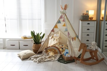 Cute wigwam with fairy lights and toys in stylish child's room © New Africa