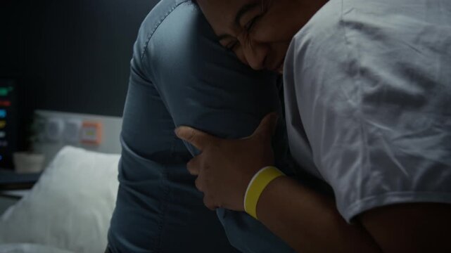 Pregnant Black woman experiencing labor pain and hugging supportive husband in hospital room. Footage is suitable for maternity care and family planning campaigns, close up