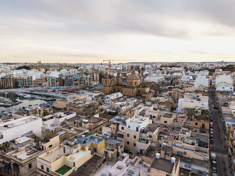 Aerial view of the historic St Joseph Parish Church and dense urban rooftops overlooking the marina under a soft sky in Msida, Eastern Region, Malta.