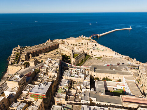 Aerial view of Fort St Elmo and the historic rooftops of the city overlooking the blue Mediterranean Sea in Valletta, Port Region, Malta.