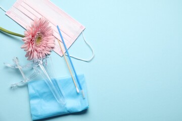 Obraz premium Sterile gynecological examination kit, medical mask and gerbera flower on light blue background, flat lay. Space for text