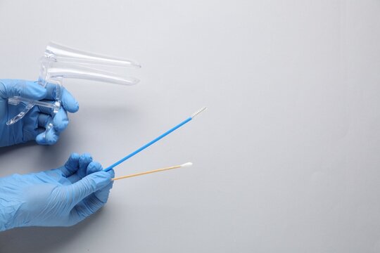 Doctor with vaginal speculum and other gynecology tools on light background, above view. Space for text