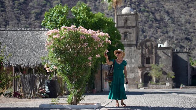 Senior woman enjoys exploring the San Javier Mission in Baja California Sur at sunrise. The scene showcases the oasis in the desert