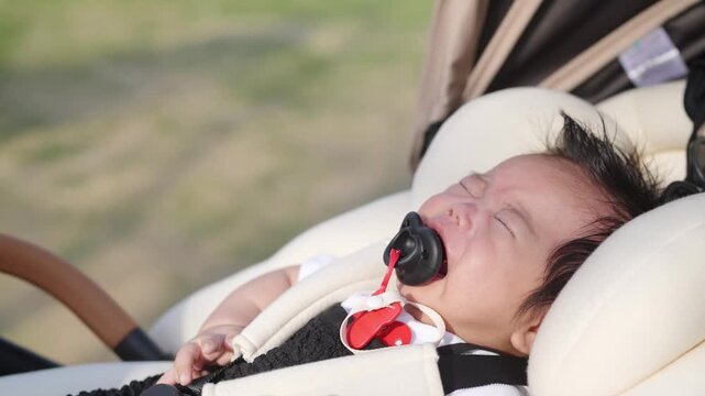 Soft sunlight bathes a sleeping infant. Tiny hands reach upward in calm repose. Gentle hand adjusts the pacifier. Baby's face shows peaceful, dreamy serenity