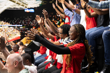 Fototapeta premium Packed stadium with cheering supporters during thrilling soccer match, raised arms. Sports fans show support and celebrate goals with emotional crowd reactions, fan chants for football culture.