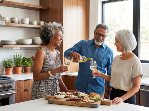 Mature seniors drinking wine together socializing at home dinner party