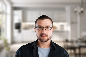 Naklejka premium Man with glasses and beard looking at camera in a modern kitchen interior