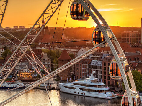 Aerial view of the AmberSky ferris wheel and a luxury yacht on the Motlawa river with historic architecture at sunset in Gdansk, Pomeranian Voivodeship, Poland.