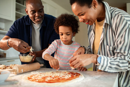 Family making homemade pizza together in kitchen