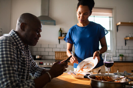 Couple clearing dinner dishes in a home kitchen