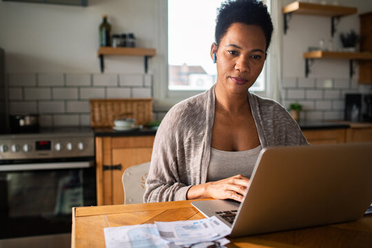 Woman managing finances on laptop at home kitchen table