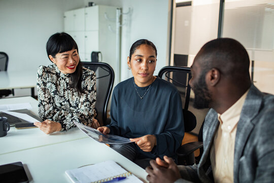 Three coworkers discussing project plans in modern office