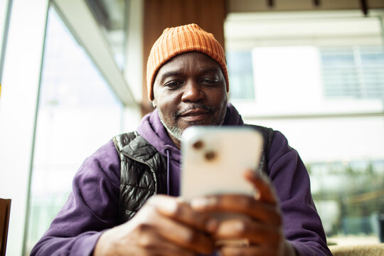Mature man texting on smartphone at cafe