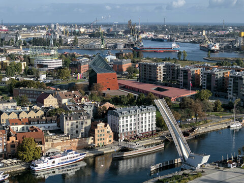 Aerial view of the Museum of the Second World War and the Olowianka Footbridge over the Motlawa River with shipyard cranes in the distance in Gdansk, Pomeranian Voivodeship, Poland.