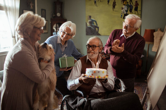 Senior friends celebrating birthday at home with cake