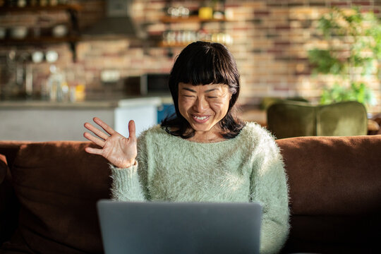 Smiling woman waving on video call in living room