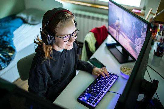 Teen girl gaming with headset at home desk