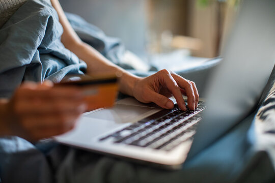 Hands paying online with credit card on laptop at home