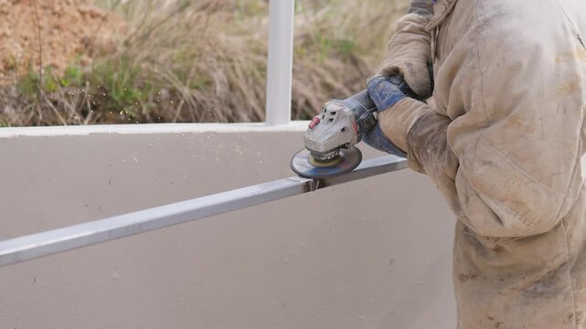 Technician Restoring Metal Fence Rail Outdoors, Midshot Of Gloved Hands Operating Angle Grinder, Surface Smoothing And Debris Removal, Protective Workwear And Focused Posture, Site Background