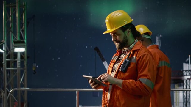 Offshore platform specialist reviewing maritime security issues using tablet during conflict affecting operations.