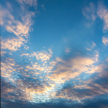 Beautiful blue sky background with golden hour clouds and orange sunset light over dramatic atmospheric altocumulus ripples