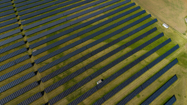 Aerial view of the Veprek Solar Park with rows of photovoltaic panels on green grass in Nova Ves u Melnika, Central Bohemian Region, Czechia.