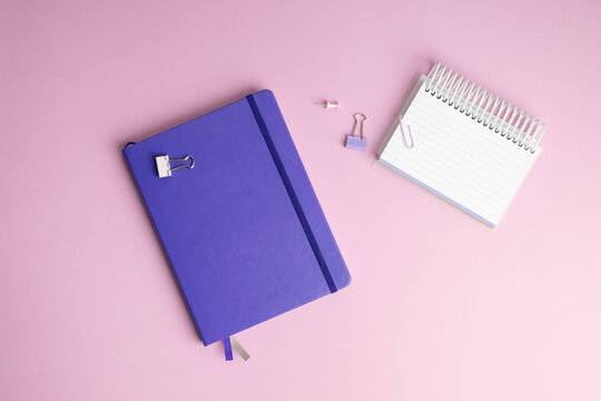 Notebooks with binder clips and push pins, purple with pink background.
