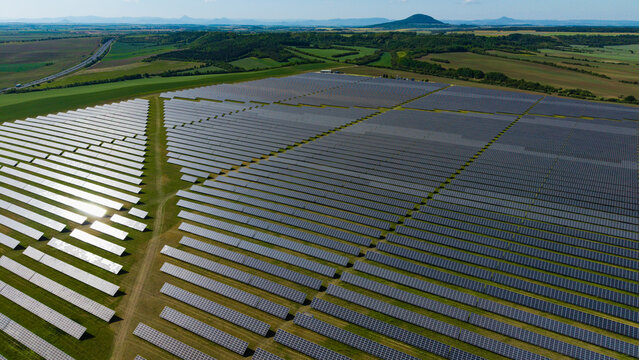 Aerial view of Veprek Solar Park with rows of photovoltaic panels across green fields in Nova Ves u Melnika, Central Bohemian Region, Czechia.