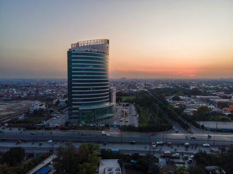 Aerial view of Arfa Kareem Tower with its modern glass facade during sunset overlooking the urban skyline and busy roads in Lahore, Punjab, Pakistan.