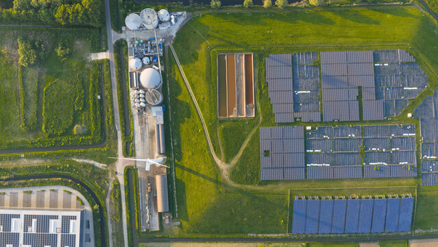Aerial view of the Wabico BV biogas plant featuring solar panels, a wind turbine, and industrial tanks surrounded by green fields in Waalwijk, Noord-Brabant, Netherlands.