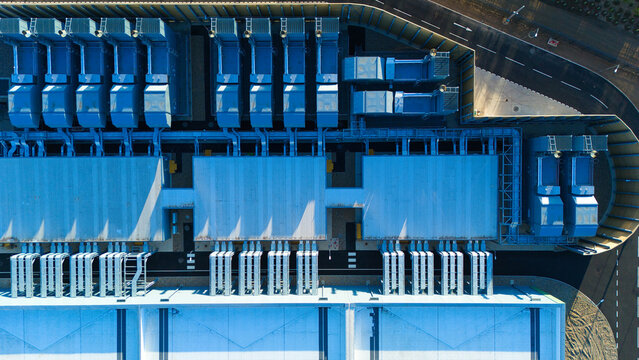 Aerial view of the Google Data Centre Waltham Cross featuring industrial cooling units, complex piping systems, and metallic rooftops in Cheshunt, England, United Kingdom.