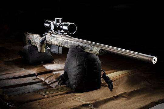 Large bolt-action rifle with riflescope on a brown shooting mat