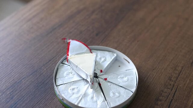 Close-up of triangle processed cream cheese portion in open foil wrapper