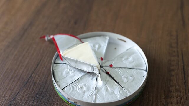 Close-up of triangle processed cream cheese portion in open foil wrapper