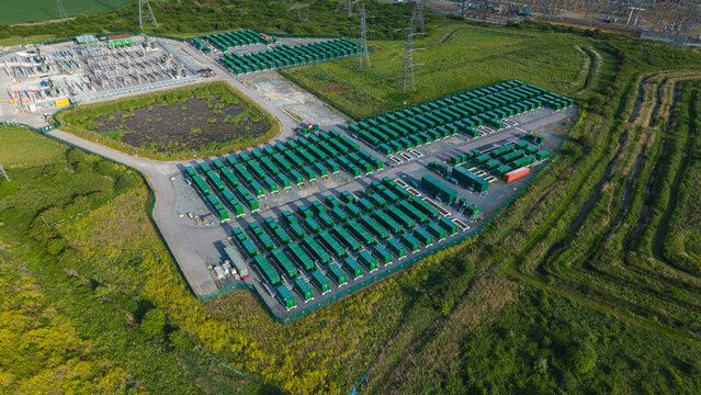 Aerial view of the Thurrock Battery Energy Storage BESS and Flexible Generation Plant with rows of green containers and power pylons in Thurrock, England, United Kingdom.