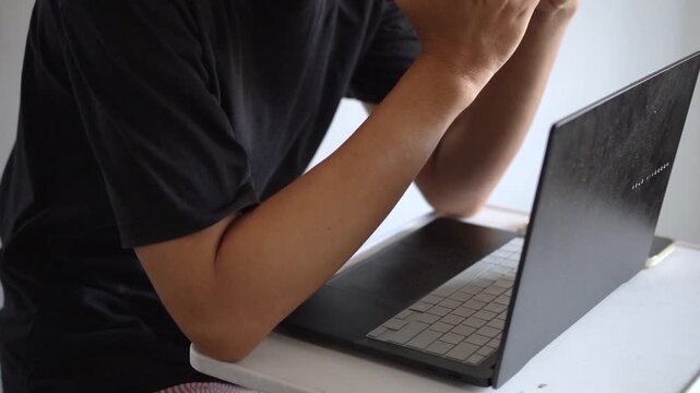 Close Up View of Sad and Stressed Man Covering His Face While Sitting in Front of Laptop