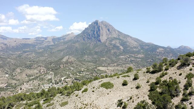 Aerial view of the imposing Puig Campana rising above the peaceful village of Orxeta in Alicante, surrounded by Mediterranean mountains, and rugged inland landscapes, sPAIN.