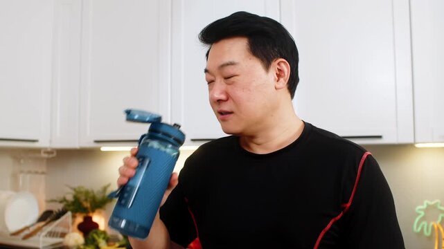 Man shakes shaker bottle in kitchen mixing water with electrolyte creatine glutamine or protein powder before training. Sports drink supports hydration muscle recovery energy healthy fitness routine.