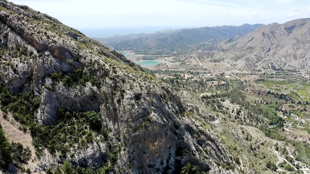 Aerial view of the imposing Puig Campana rising above the peaceful village of Orxeta in Alicante, surrounded by Mediterranean mountains, and rugged inland landscapes, sPAIN.