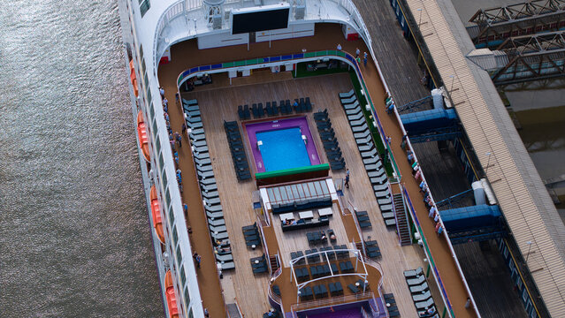 Aerial view of the upper deck of a cruise ship featuring a swimming pool and lounge chairs docked at the London International Cruise Terminal in Tilbury, England, United Kingdom.