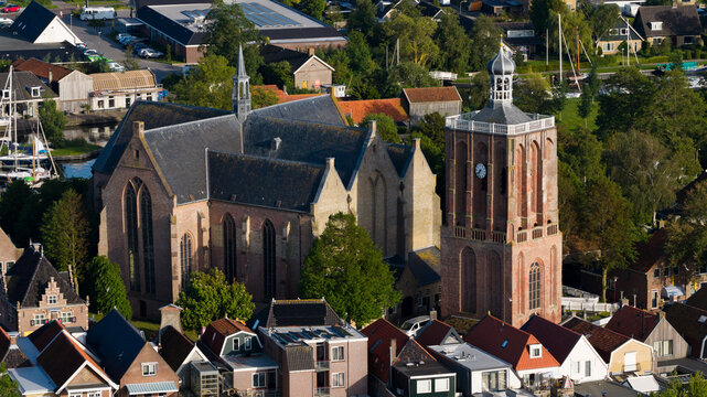 Aerial view of the historic St. Gertrude's Church with its prominent brick bell tower and surrounding traditional rooftops in Workum, Friesland, Netherlands.