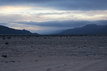 Fototapeta premium Moonrise Over Mountain Range in Desert at Dusk